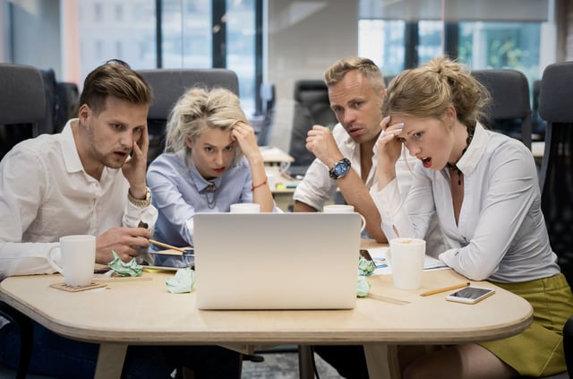 Frustriertes Team schaut auf die Bildschirme ihrer Laptops